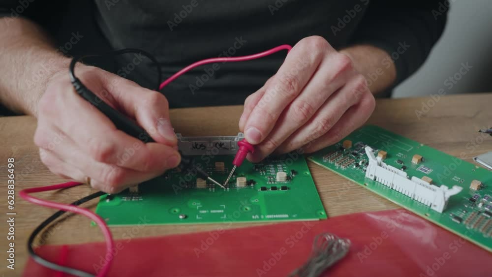 Man is checking the circuit of an electronic board with a multimeter and soldering the board component. Fixing electronics. Man is checking the circuit of an electronic board with a multimeter and soldering the board component. Fixing electronics.