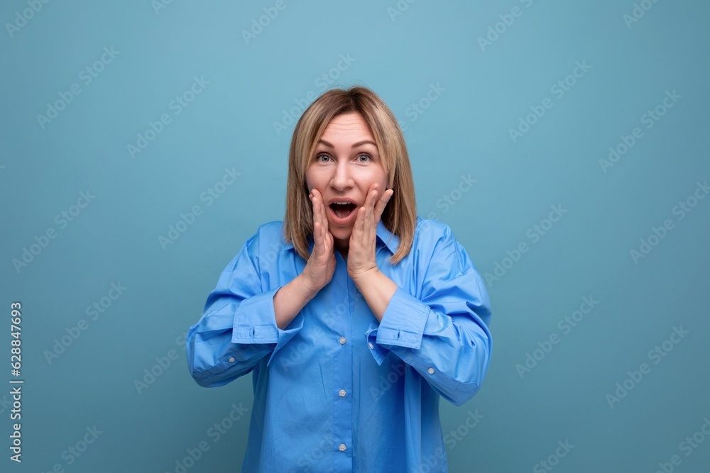 shocked surprised young woman in casual look grabbing her head on blue background shocked surprised young woman in casual look grabbing her head on blue background