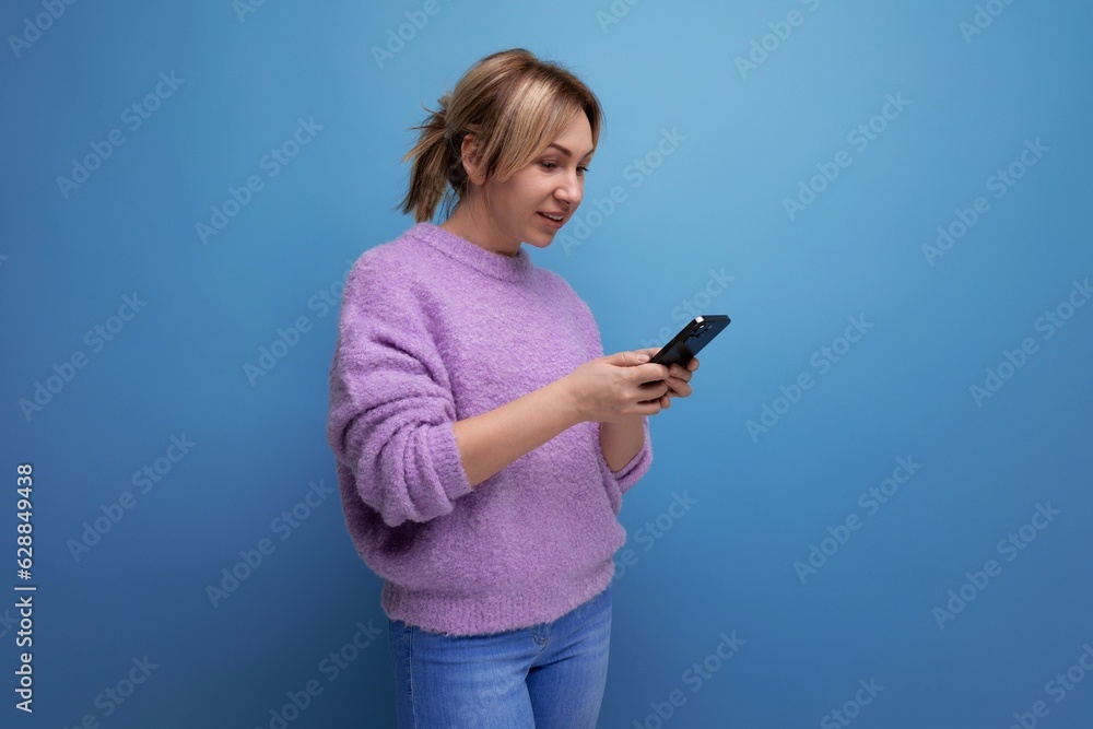attractive blond young millennial woman in casual look chatting in smartphone on bright background with copy space attractive blond young millennial woman in casual look chatting in smartphone on bright background with copy space