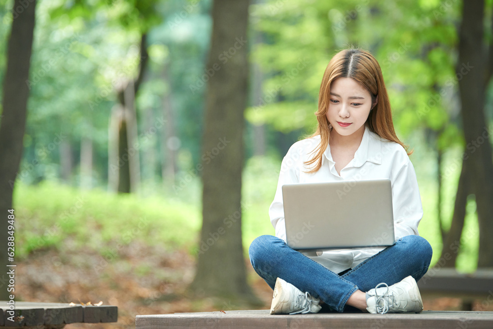 A young woman using a laptop in the park, a college student