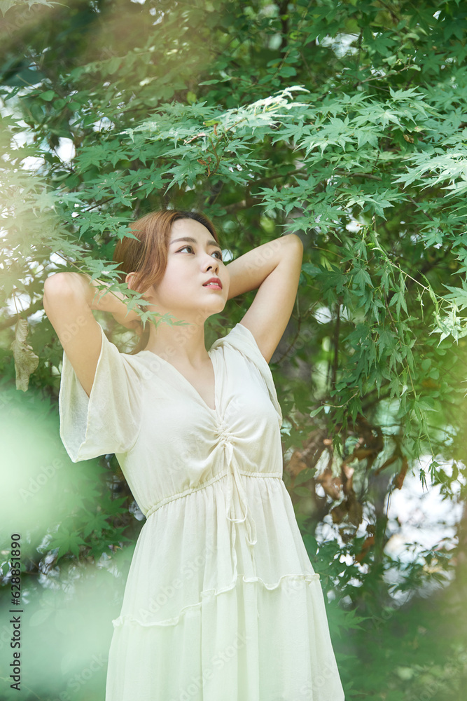 In summer daytime, a beautiful Asian woman wearing a dress in a forested park is doing various movements. In summer daytime, a beautiful Asian woman wearing a dress in a forested park is doing various movements.