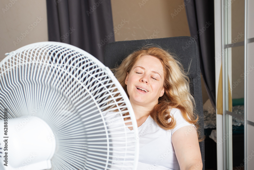 Woman using a fan to circulate air in her home during the summer