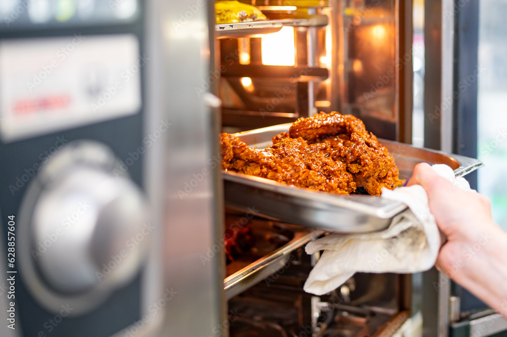chef of the restaurant puts a baking tray with chicken in the oven for cooking on kitchen chef of the restaurant puts a baking tray with chicken in the oven for cooking on kitchen