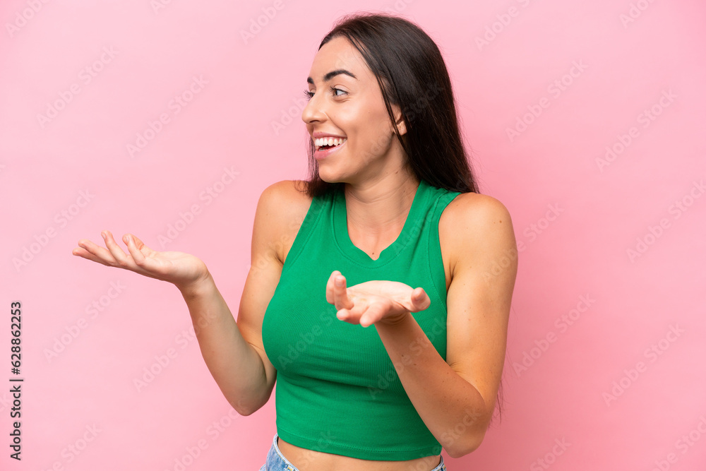 Young caucasian woman isolated on pink background with surprise expression while looking side