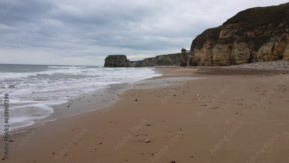 Walking Along the Seashore With Rocks and People in the Distance (Marsden Beach, England) Walking Along the Seashore With Rocks and People in the Distance (Marsden Beach, England)