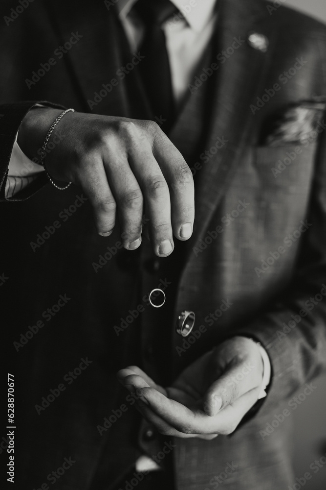 the groom throws gold wedding rings in his hands. Black and white photo
