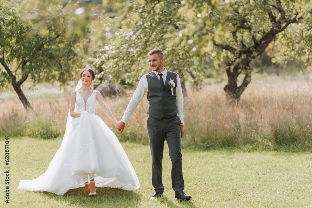 A beautiful wedding, a beautiful couple in love, walking on the background of a green garden with tall green trees. High quality photo