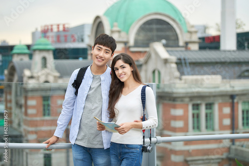 During the trip, a college student couple is looking for their way with a map at Seoul Station during the day.