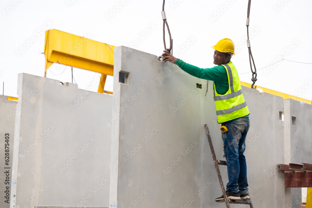 Reinforced concrete structures. Man construction worker control large crane for placing precast concrete panels at Heavy Industry Manufacturing Factory Reinforced concrete structures. Man construction worker control large crane for placing precast concrete panels at Heavy Industry Manufacturing Factory