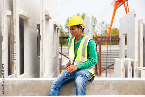 Tired hot wiping sweat. Asian worker enjoying free time. forman warehouse worker sitting on workshop site break relax time at Heavy Industry Manufacturing Prefabricated concrete walls Factory