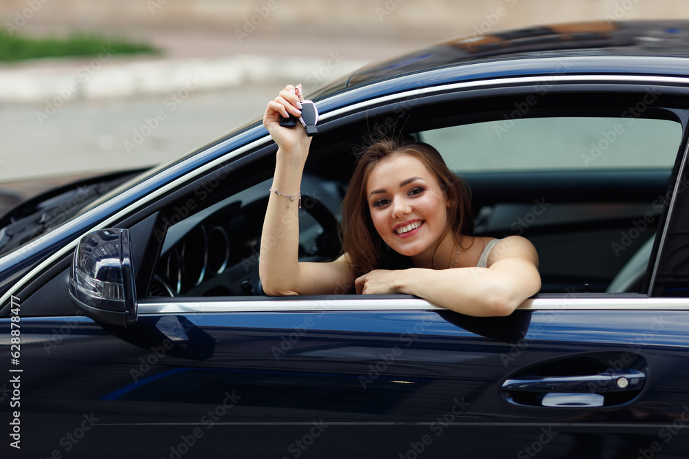 Happy woman driver with key car smiling. Cute young happy brunette female driving car vehicle