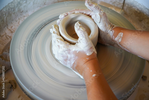 top view of kid making ceramic pot on pottery wheel  