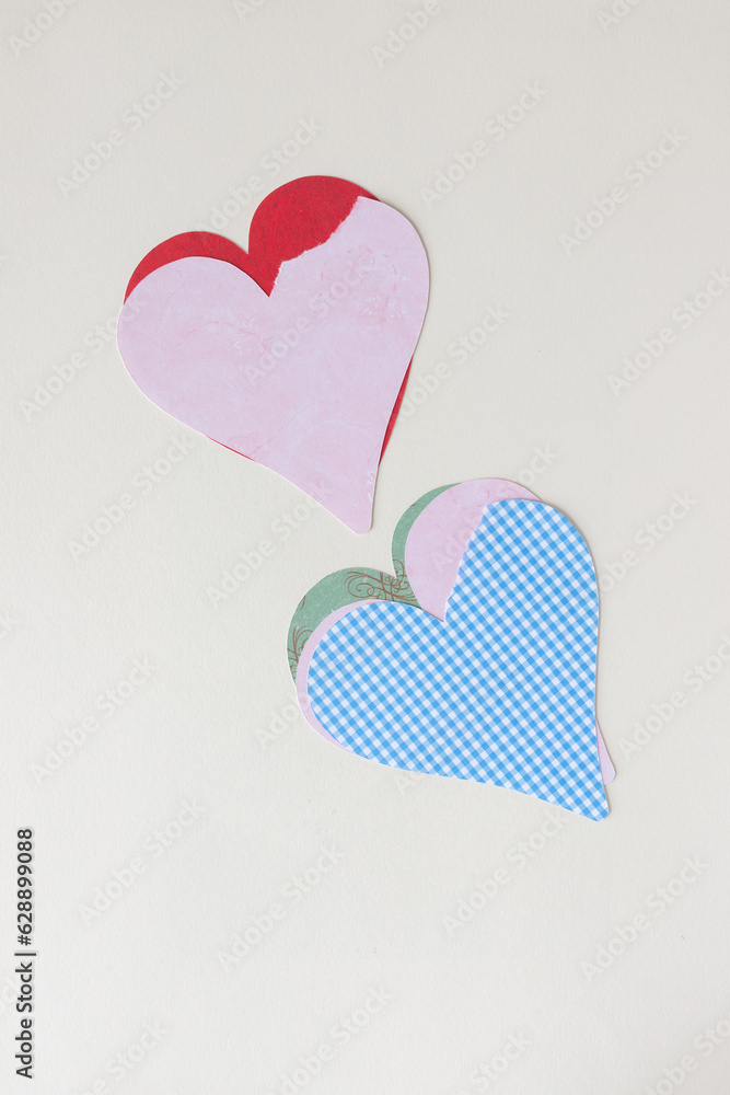two piles of imperfect machine-cut paper hearts on blank paper