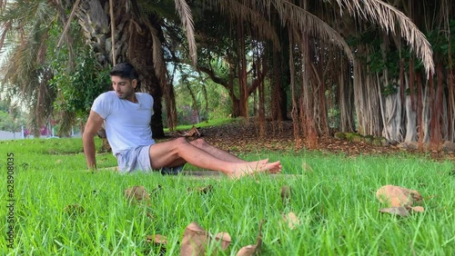 Joven indio entrenando yoga. Sesión de fitness en colchoneta en el parque. Relax al aire libre para una buena salud. Ejercicios para una mejor movilidad por las mañanas en verano en canarias.  photo