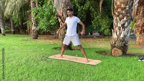 Joven indio entrenando yoga. Sesión de fitness en colchoneta en el parque. Relax al aire libre para una buena salud. Ejercicios para una mejor movilidad por las mañanas en verano en canarias.  photo