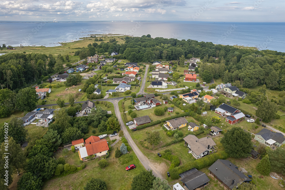 Aerial view of a little European beachfront village with private houses surrounded by trees and sea, village on island, resort town.  