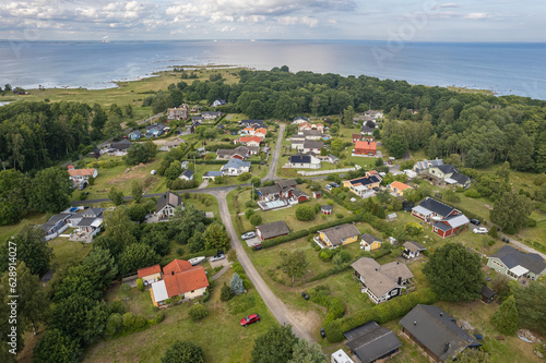 Aerial view of a little European beachfront village with private houses surrounded by trees and sea, village on island, resort town. 