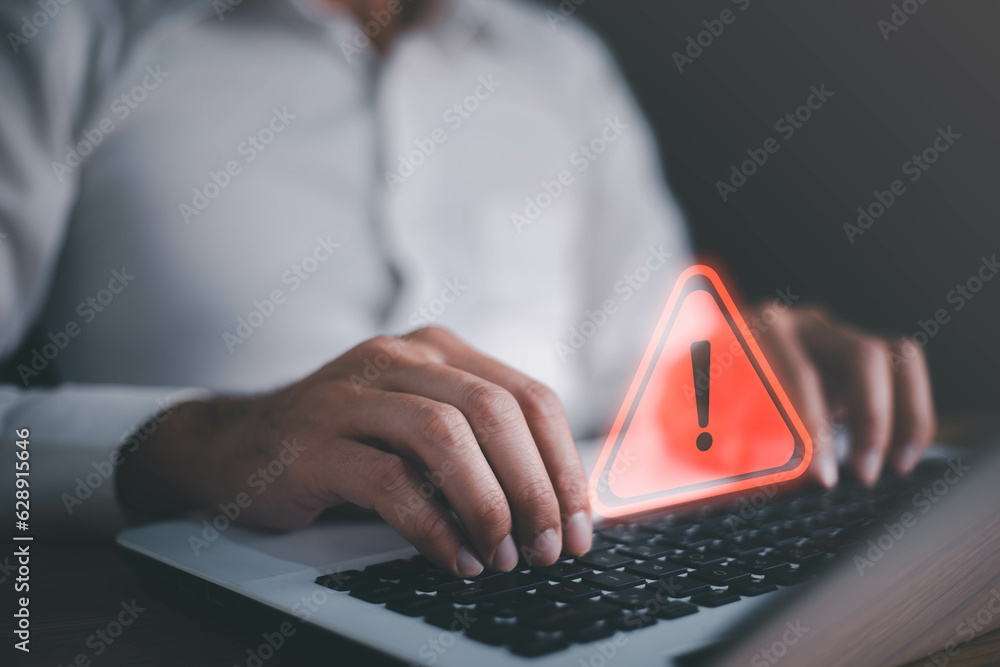 © Suriya - Businessman or it staffs, programmer, developer using computer laptop with triangle caution warning sign for notification error and maintenance concept. Virus detected warning, Cybercrime protection