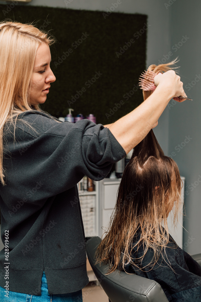 Fototapeta premium A hairdresser cuts a blonde's hair in a beauty salon. Women's haircut