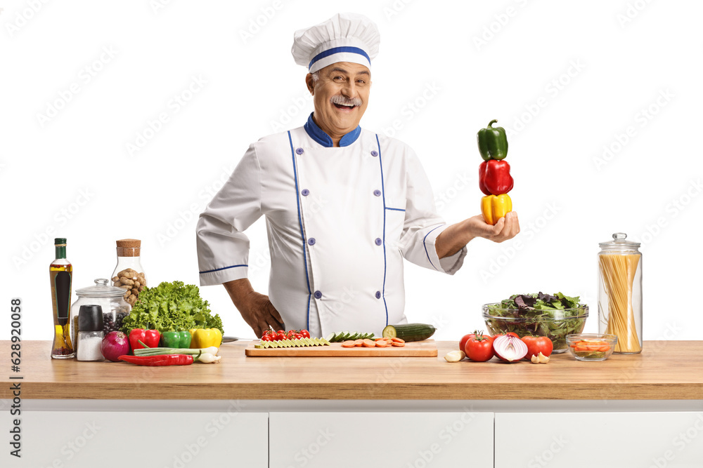 Cheerful mature male chef smiling and holding bell peppers Cheerful mature male chef smiling and holding bell peppers