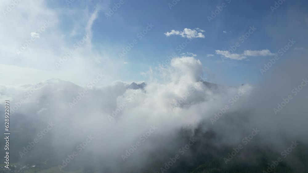 Landscape scene of smoke over canyon of green mountains with snowy top and hazy sky Landscape scene of smoke over canyon of green mountains with snowy top and hazy sky