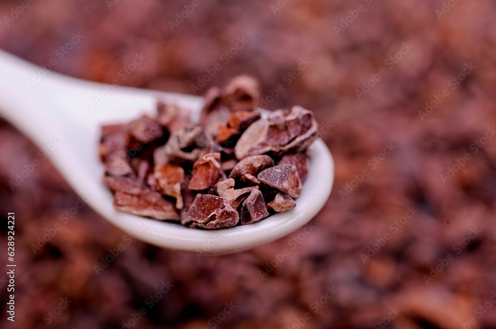 Close-up of organic raw cacao nibs in a spoon on a table Close-up of organic raw cacao nibs in a spoon on a table