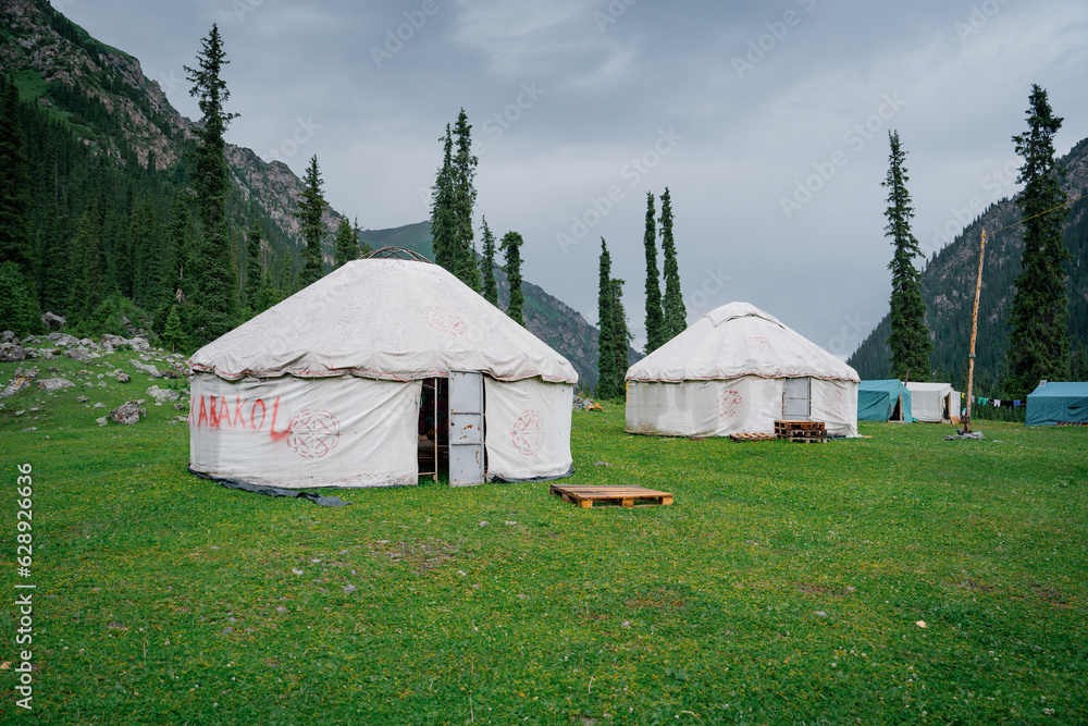 Two Kyrgyz yurts on grass in middle of the mountains. Yurts are traditional national buildings of local residents