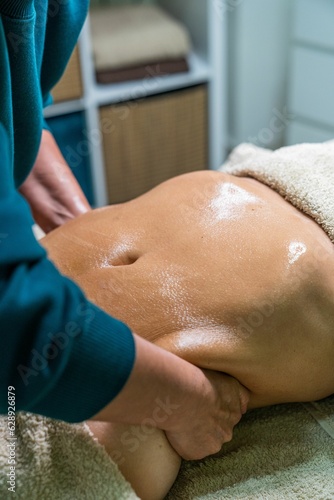 Masseur performing lymphatic drainage massage on the side of the patient's abdomen.