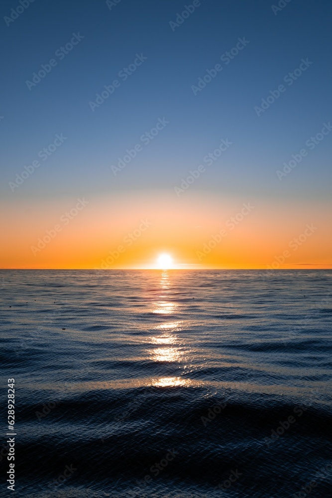 Vibrant vertical shot of the sun setting over the Atlantic Ocean