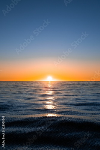 Vibrant vertical shot of the sun setting over the Atlantic Ocean