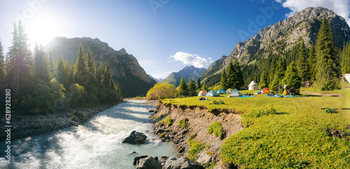 River and tent houses with yurt in the mountain valley of Altyn Arashan gorge, Kyrgyzstan. Morning vibes. Sun rays. Sunrise photo