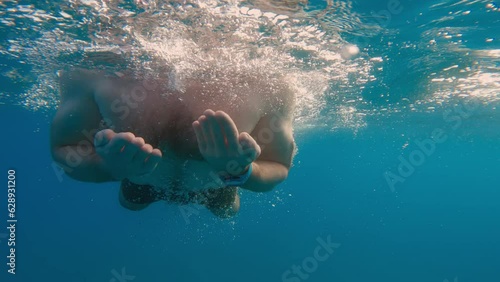 Boy is swimming breaststroke style in the open ocean underwater photo