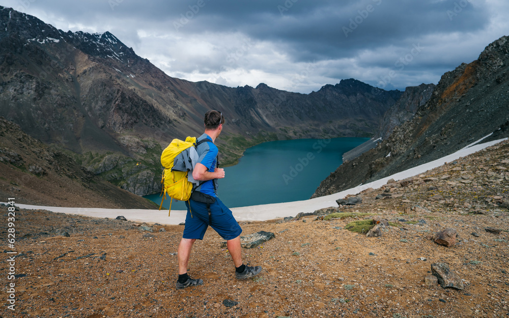 Mountain guide in sportswear. High-altitude hiking. A man feeling successful as he achieves his goals. Motivation every day. A tourist with a yellow backpack, determined to reach the mountain summit.
