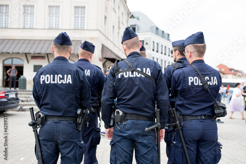 Polish policemen stand with their backs to the camera.