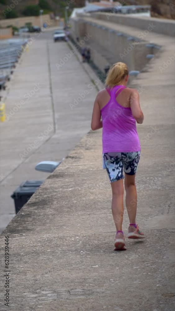 Slow motion, young girl with her back turned running along the pier of the port Slow motion, young girl with her back turned running along the pier of the port