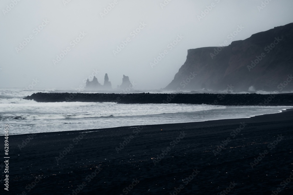 Idyllic beach scene in Reykjavik, Iceland featuring black sand and a foggy weather