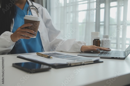 Confident doctor man holding a pill bottle and writing while talking with senior patient and reviewing his medication at office room.