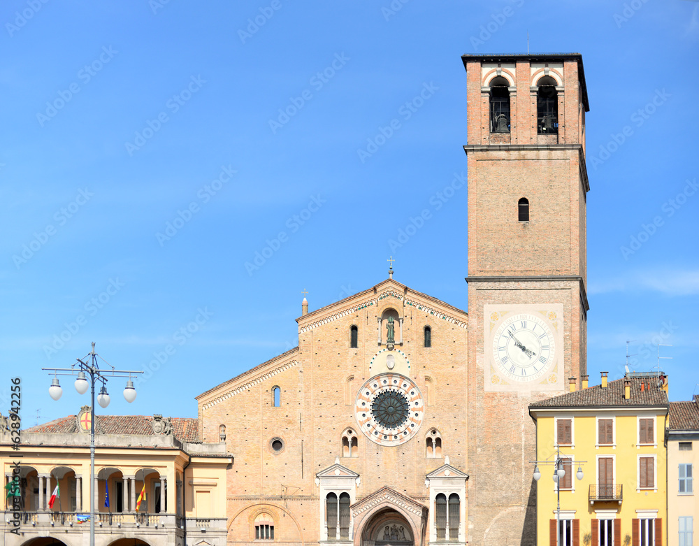 Roman catholic cathedral (also called duomo or basilica) with typical houses next to it against blue sky in Lodi, Lombardy, Italy