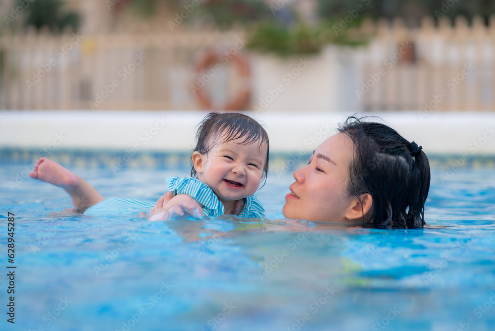 happy and beautiful Asian woman holding her little baby girl playful - Korean mother and adorable daughter playing on water at resort swimming pool in Summer happy and beautiful Asian woman holding her little baby girl playful - Korean mother and adorable daughter playing on water at resort swimming pool in Summer