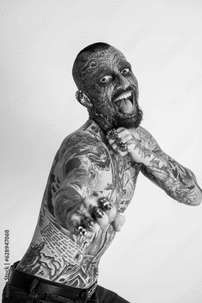 Shirtless tattooed male posing against white background