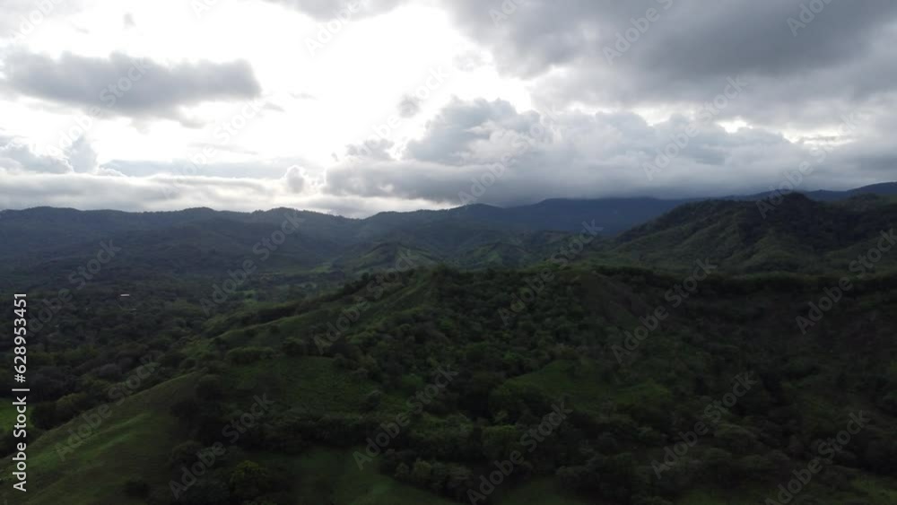 Aerial of dense green forests and mountains under the cloudy sky Aerial of dense green forests and mountains under the cloudy sky
