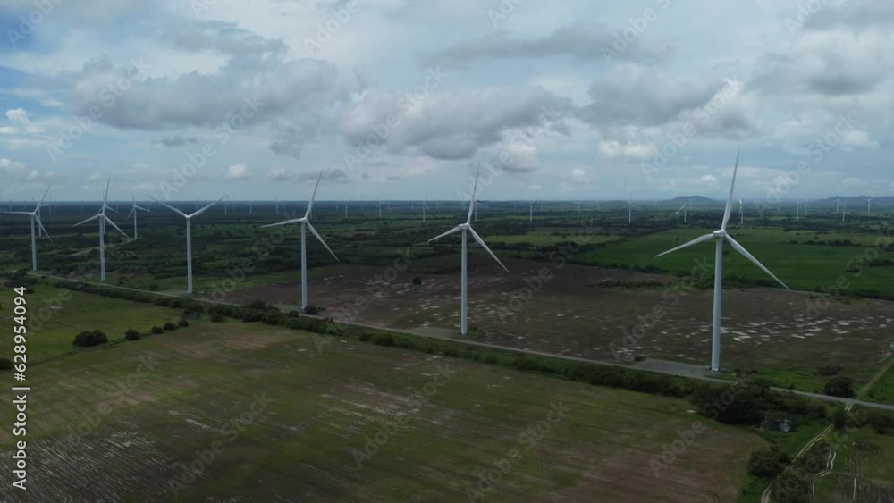 Aerial of wind turbines working in the wide field during the daytime under the cloudy sky