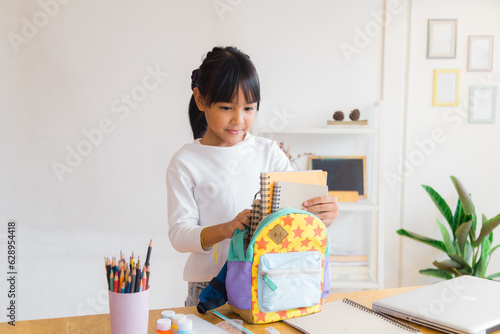 Pupil child put books and notes into backpack. School supplies.Back to school concept. Kid prepare for studies. Portrait cute little girl packing backpack .