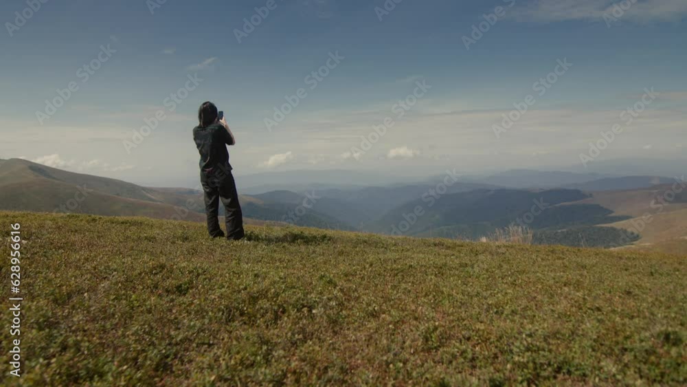 Aerial video of a girl taking pictures on the top of rocky mountain Aerial video of a girl taking pictures on the top of rocky mountain
