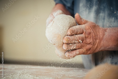 the person is making a dough on a wood table in the kitchen