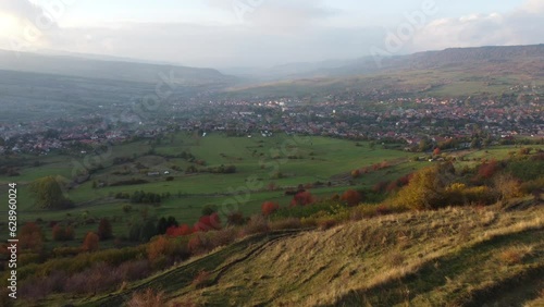 Drone view of a wooden arch on a hill with a background of country houses between mountains photo