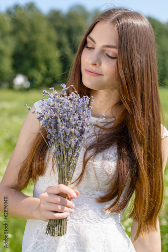 Beautiful young woman with a bouquet of lavender at a flowery meadow in summer