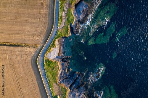 Aerial view of the Hookhead Lighthouse overlooking a yellow field in Ireland