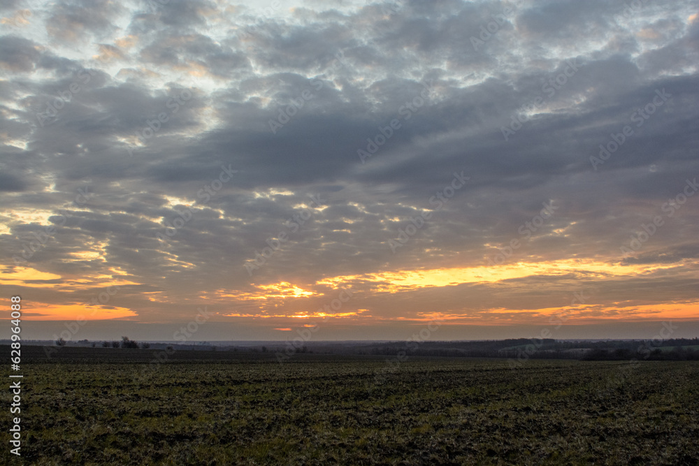 fields and hills against a sky with a large number of clouds, illuminated by a bright sunset light, during the golden hour fields and hills against a sky with a large number of clouds, illuminated by a bright sunset light, during the golden hour
