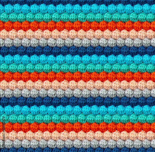 Geometric volumetric seamless knitted pattern in the form of bumps. The texture is crocheted from multi-colored yarn. Pastel contrasting color combination.